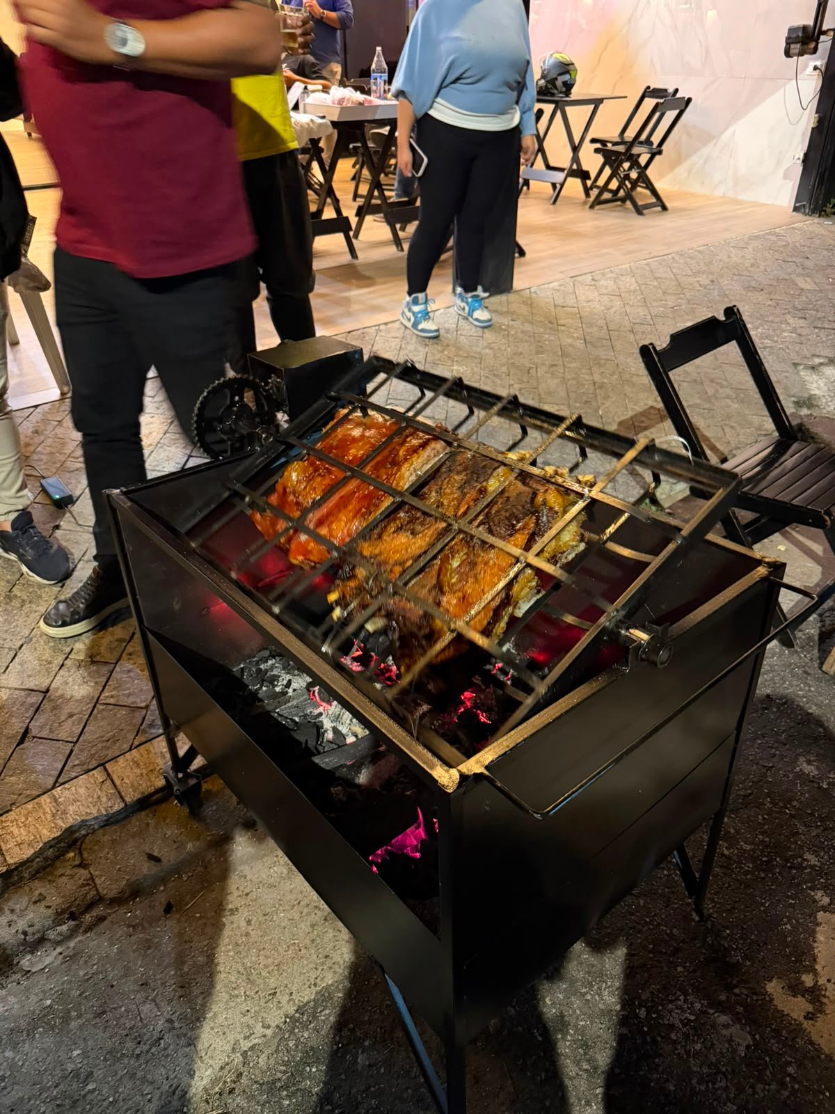 Carne assando na churrasqueira Brasa Viva durante evento noturno